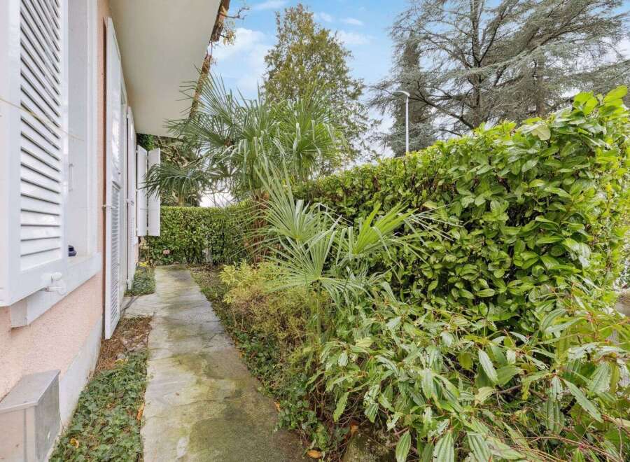 Discover the charm of this property, featuring a serene pathway lined with lush greenery.