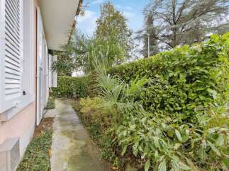 Discover the charm of this property, featuring a serene pathway lined with lush greenery.