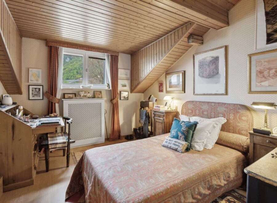 Discover the charm of this cozy bedroom, featuring a unique wooden ceiling and a quaint desk area.