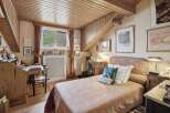 Discover the charm of this cozy bedroom, featuring a unique wooden ceiling and a quaint desk area.