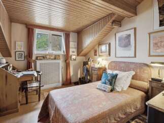 Discover the charm of this cozy bedroom, featuring a unique wooden ceiling and a quaint desk area.