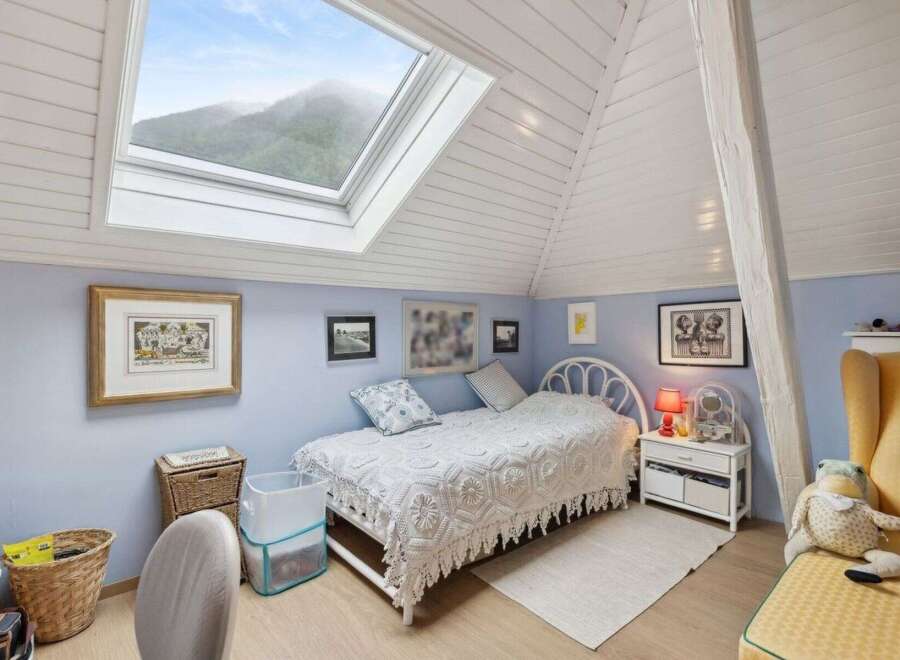 This charming bedroom features a unique design with a skylight that offers stunning views of the surrounding mountains.