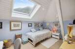This charming bedroom features a unique design with a skylight that offers stunning views of the surrounding mountains.