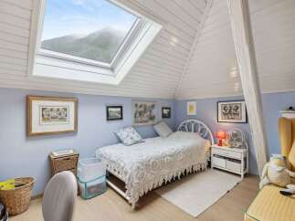 This charming bedroom features a unique design with a skylight that offers stunning views of the surrounding mountains.