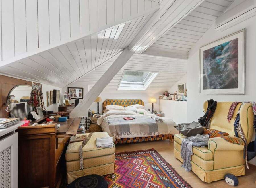 This charming bedroom boasts a unique architectural design with its sloped ceilings and skylight, creating a bright and airy atmosphere.