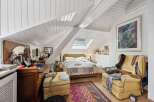 This charming bedroom boasts a unique architectural design with its sloped ceilings and skylight, creating a bright and airy atmosphere.