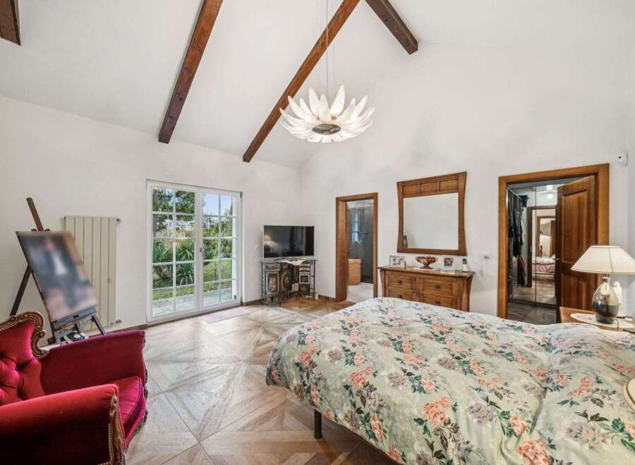 Step into luxury in this stunning bedroom, featuring a unique design with exposed wooden beams and a statement chandelier.