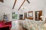 Step into luxury in this stunning bedroom, featuring a unique design with exposed wooden beams and a statement chandelier.