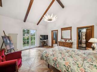 Step into luxury in this stunning bedroom, featuring a unique design with exposed wooden beams and a statement chandelier.