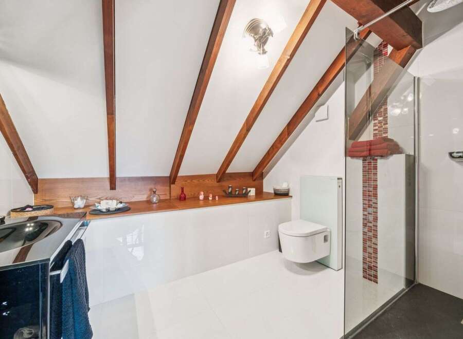 This stunning bathroom boasts a unique design with exposed wooden beams and a modern aesthetic.
