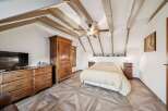 This charming bedroom boasts a unique design with exposed wooden beams and a stylish ceiling fan.