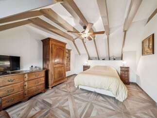 This charming bedroom boasts a unique design with exposed wooden beams and a stylish ceiling fan.