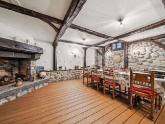 Step into rustic elegance with this stunning property, featuring a grand stone fireplace and exposed wooden beams that exude warmth and charm.