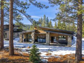 Nestled in a serene, snow-covered landscape, this stunning property boasts a modern architectural design with a blend of natural elements.