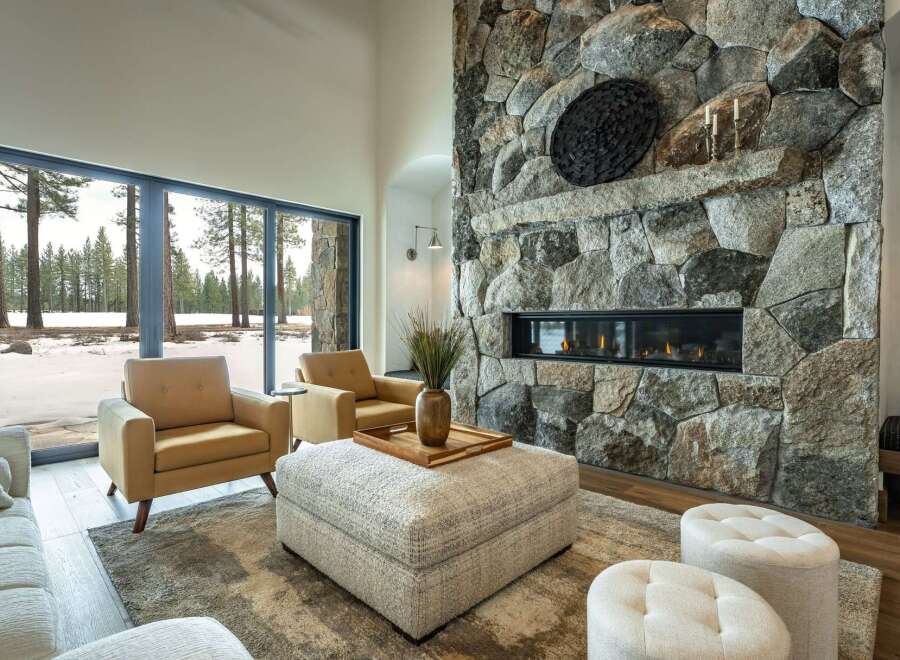 Experience luxury living in this stunning property, featuring a cozy living room with a stone fireplace and large windows.