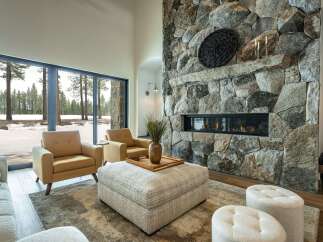 Experience luxury living in this stunning property, featuring a cozy living room with a stone fireplace and large windows.