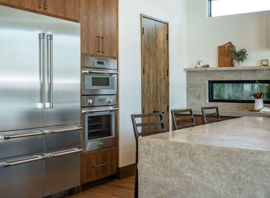 This stunning kitchen boasts high-end stainless steel appliances, including a refrigerator, oven, and microwave, seamlessly integrated into custom cabinetry.