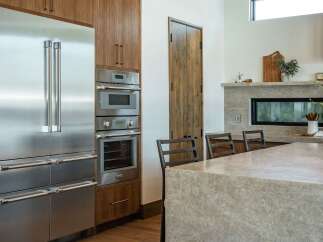 This stunning kitchen boasts high-end stainless steel appliances, including a refrigerator, oven, and microwave, seamlessly integrated into custom cabinetry.