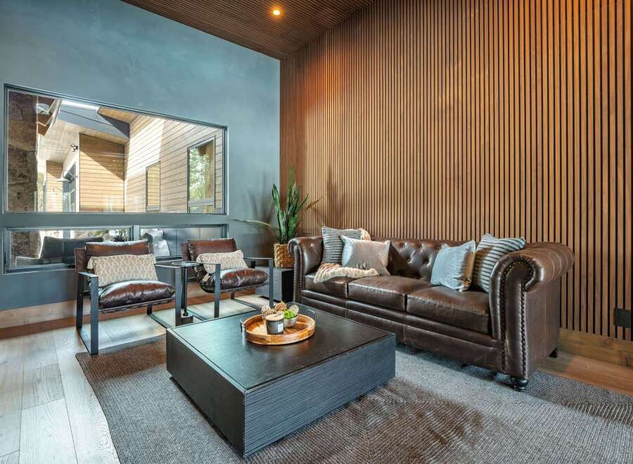 Step into luxury with this stunning living room, featuring a cozy leather sofa and elegant wood paneling.