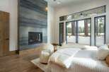 Experience luxury living in this stunning bedroom featuring a modern fireplace and expansive windows.