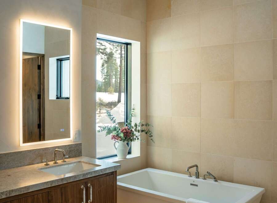 This luxurious bathroom features a modern design with a sleek, freestanding bathtub and a large, illuminated mirror.