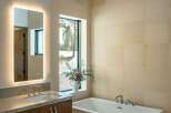 This luxurious bathroom features a modern design with a sleek, freestanding bathtub and a large, illuminated mirror.
