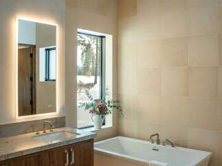 This luxurious bathroom features a modern design with a sleek, freestanding bathtub and a large, illuminated mirror.