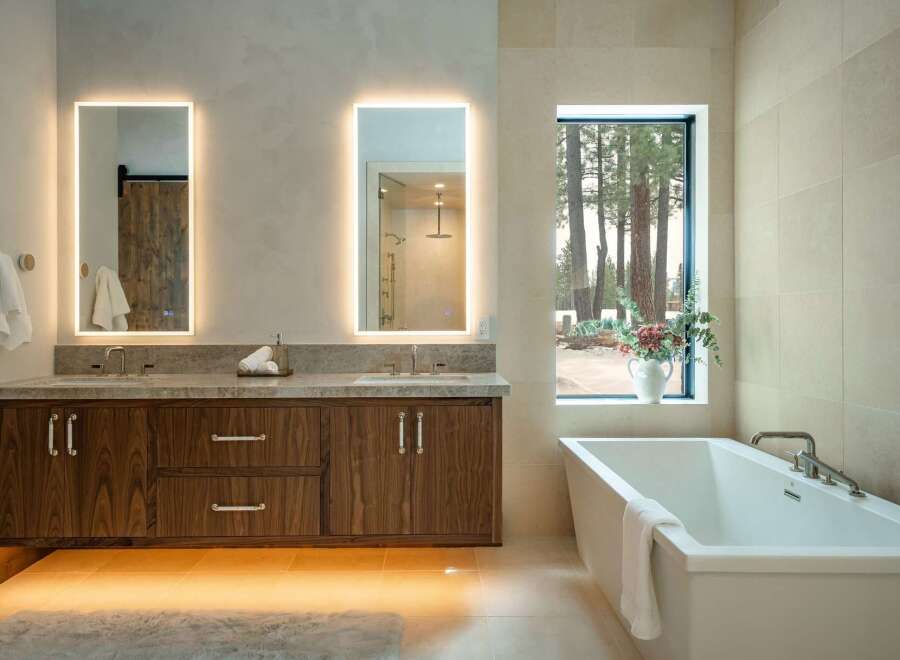 This luxurious bathroom boasts a modern design with a floating wooden vanity and sleek, illuminated mirrors.