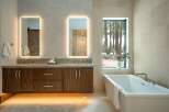 This luxurious bathroom boasts a modern design with a floating wooden vanity and sleek, illuminated mirrors.