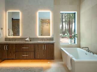 This luxurious bathroom boasts a modern design with a floating wooden vanity and sleek, illuminated mirrors.