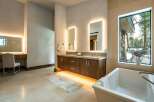 Step into luxury with this stunning bathroom, featuring a sleek double vanity with illuminated mirrors and a modern soaking tub.
