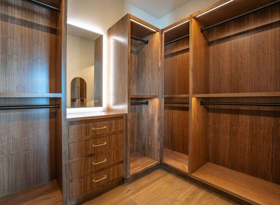 Step into luxury with this stunning walk-in closet, featuring custom wood cabinetry and ample storage space.