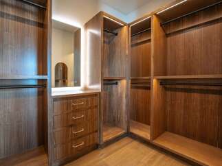 Step into luxury with this stunning walk-in closet, featuring custom wood cabinetry and ample storage space.
