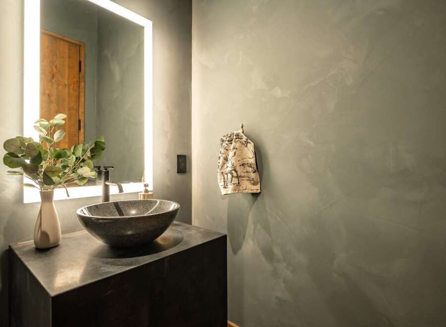 This modern bathroom features a sleek design with a dark countertop and a stylish vessel sink.