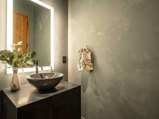 This modern bathroom features a sleek design with a dark countertop and a stylish vessel sink.