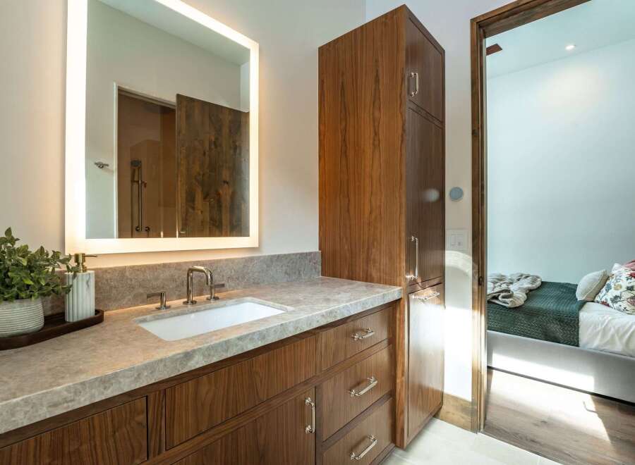 This stunning bathroom boasts a modern design with a sleek vanity and a large, illuminated mirror.