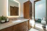 This stunning bathroom boasts a modern design with a sleek vanity and a large, illuminated mirror.