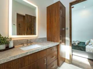 This stunning bathroom boasts a modern design with a sleek vanity and a large, illuminated mirror.