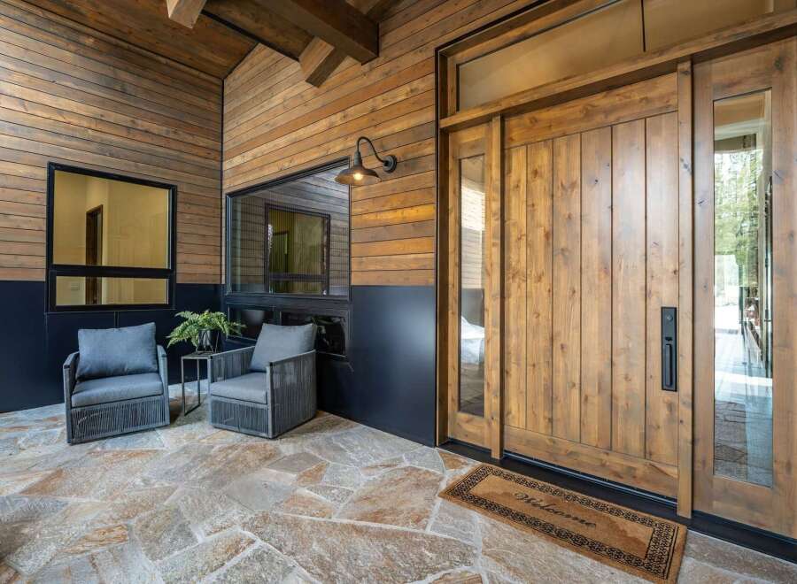 Step into luxury with this stunning property, showcasing a beautifully crafted wooden door and inviting outdoor seating area.