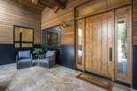 Step into luxury with this stunning property, showcasing a beautifully crafted wooden door and inviting outdoor seating area.