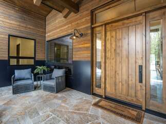 Step into luxury with this stunning property, showcasing a beautifully crafted wooden door and inviting outdoor seating area.