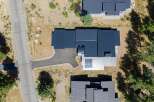 Experience modern luxury with this stunning aerial view of a contemporary home featuring a sleek dark metal roof and a unique silver metal facade.
