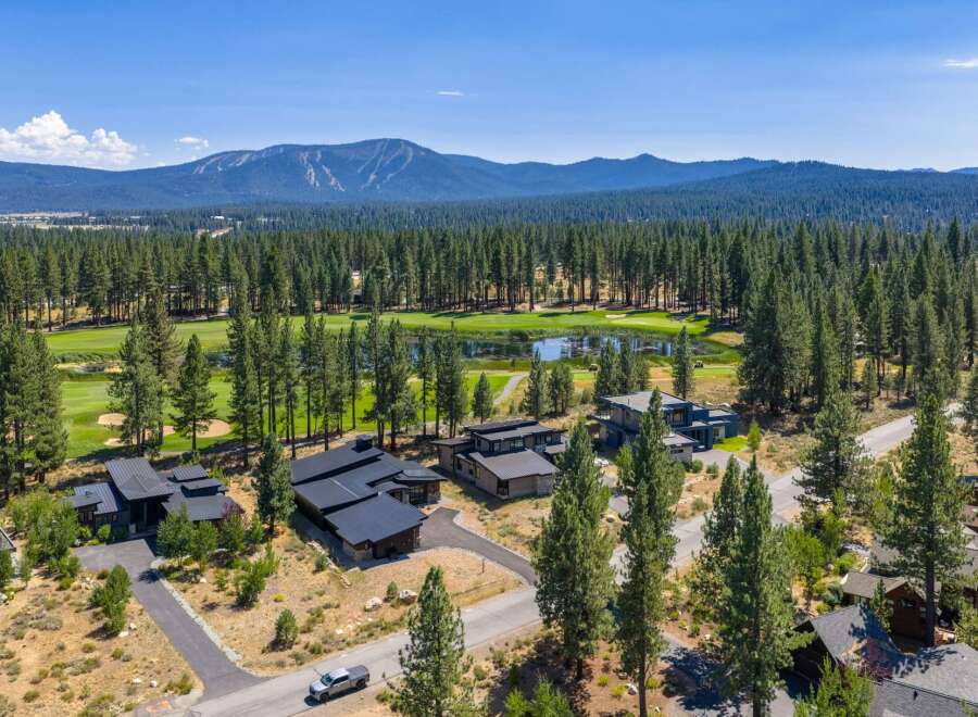 Experience luxury living adjacent to a pristine golf course, surrounded by a dense forest of mature pine trees.