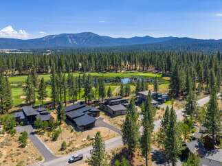 Experience luxury living adjacent to a pristine golf course, surrounded by a dense forest of mature pine trees.