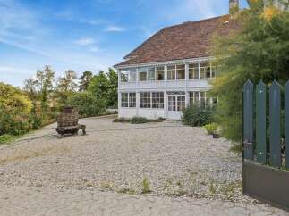 Discover this charming property featuring a classic white house with a distinctive sunroom, perfect for enjoying natural light year-round.