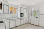 This bright and airy kitchen features modern white cabinetry with sleek gray trim, offering ample storage and a clean aesthetic.
