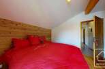 Discover the charm of this cozy bedroom featuring a striking wooden accent wall and a vibrant red bedspread.