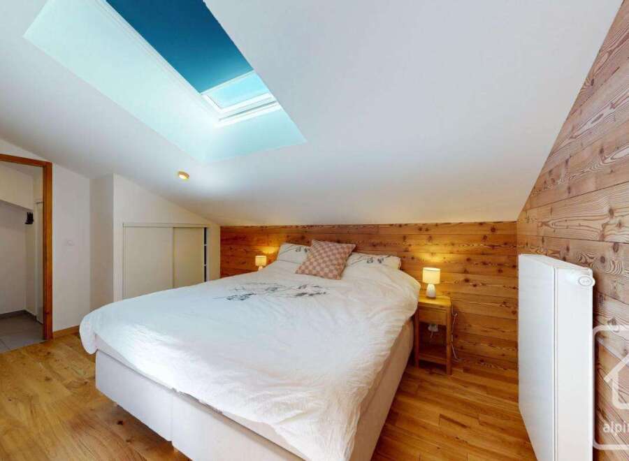 Discover the charm of this cozy bedroom featuring a unique wooden accent wall and a skylight that floods the space with natural light.