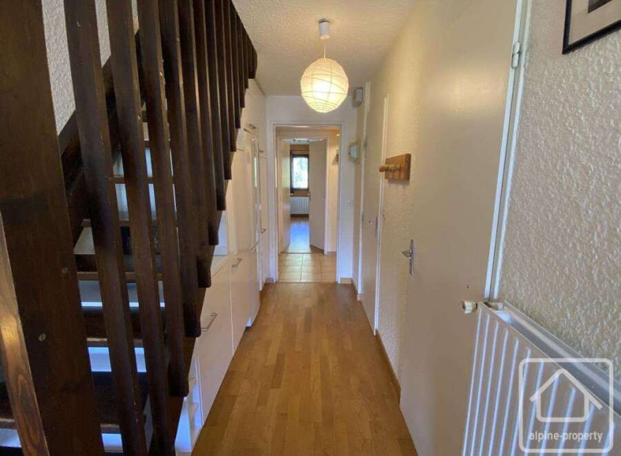 Discover this inviting property featuring a well-lit hallway with wooden flooring and a staircase.