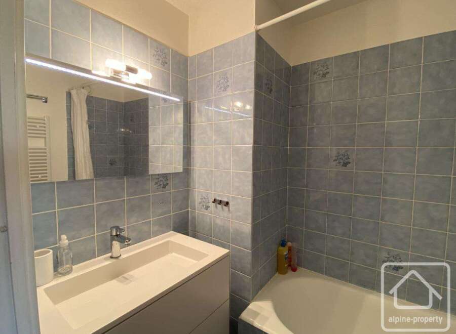 This bathroom features a modern design with blue tiled walls and a sleek white vanity.